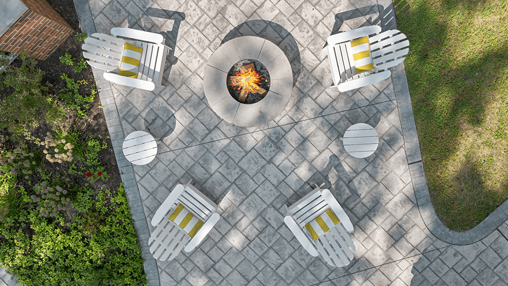 Aerial view of a patio with four white chairs, a fire pit, and planters.